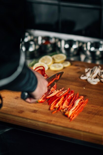 Diner chef-kok die een mes vasthoudt en rode paprika snijdt