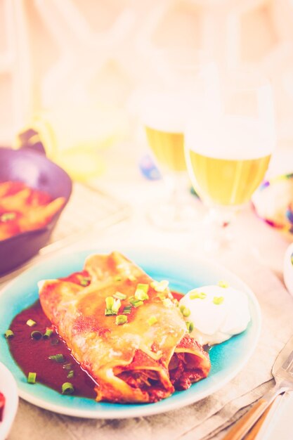 Dinerbord met Kip enchiladas gegarneerd met groene uien en zure room.