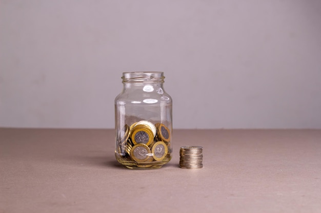 Dinero en monedas dominicanas en un frasco de vidrio. ahorro del concepto financiero