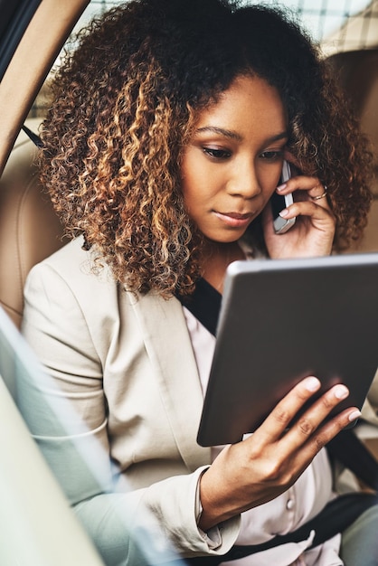 Dingen voor elkaar krijgen, zelfs als ze pendelt Shot van een aantrekkelijke zakenvrouw die belt en een tablet gebruikt tijdens haar woon-werkverkeer