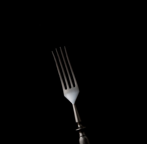 Dining fork isolated on black background with copy space