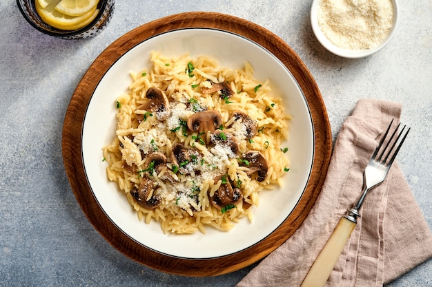 식사 이탈리안 파스타 리조니, 버섯, 소스, 파마산 치즈, 타임, 마늘, 올리브 오일, 하얀 접시에