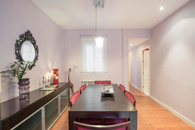 Dining room of vacation rental apartment with dark wood furniture with mirror decorative giraffe vase and lilac painted walls