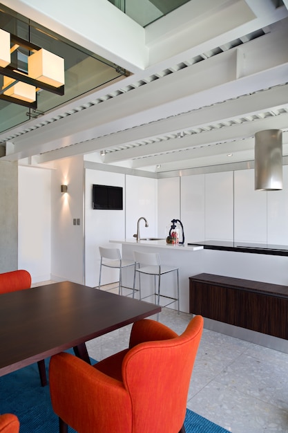 Dining room view and white kitchen inside modern and luxurious apartment.