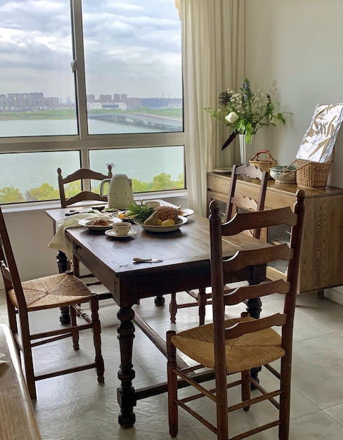 A dining room with a view of the river and a table with chairs and a table with a bread on it.