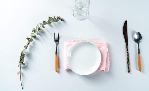 Dining set up with empty plate set placed with a knife and fork on white background