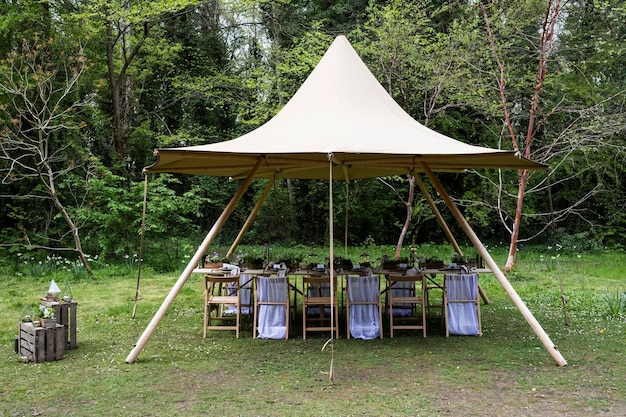 Photo dining table and chairs under a canopy for a woodland naming ceremony