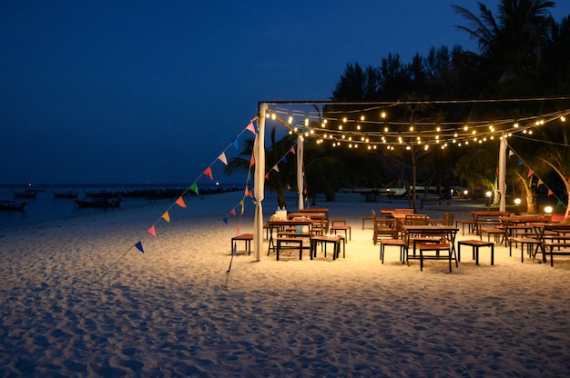 Dining table set decoration with lamp glowing and colors flag on the beach