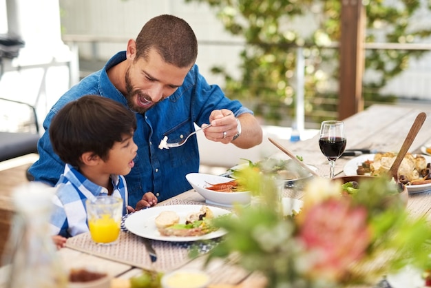 Dining with my little champ Shot of a father feeding his young son while having a meal together outdoors