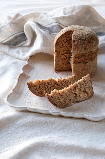 독일어로 철자된 통밀 빵을 의미하는 Dinkelbrot는 밀 대안 Dinkel 또는 Spelled는 린넨 수건이 있는 흰색 직물 배경에서 유럽에서 유기농으로 재배된 고대 곡물입니다.