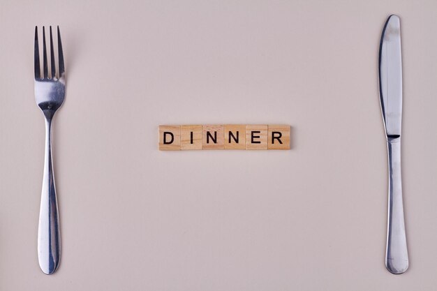 Dinner inscription on wooden blocks Fork and knife on white background