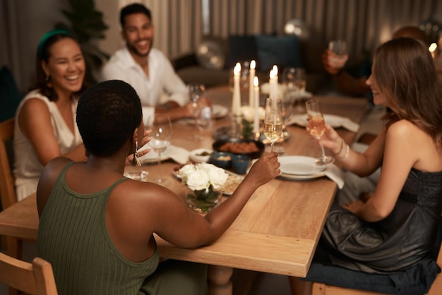新年を祝う友人とのディナー パーティーとシャンパン トースト 社交イベントのお祝いとワイングラスを持つ人々 の幸せなグループが一緒に笑ったり、休日の時間を楽しんだり