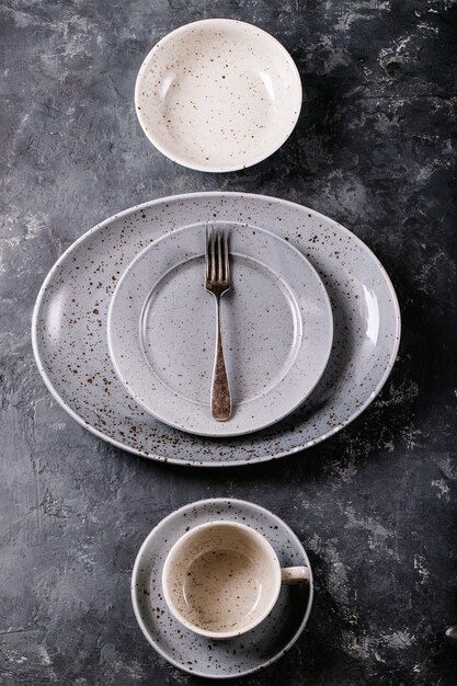 Dinner place setting. A blue modern ceramic plate with silver fork over dark texture surface. Top view, flat lay. 