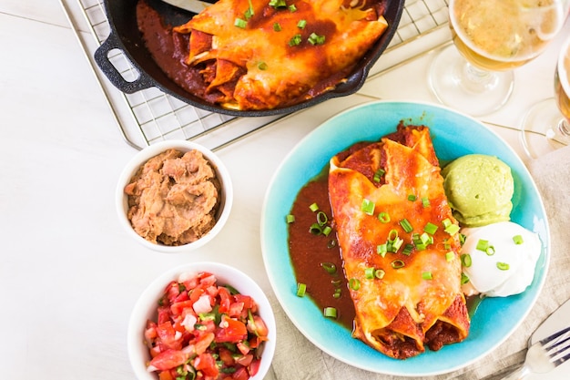 Dinner plate with Chicken enchiladas garnished with green onions and sour cream.