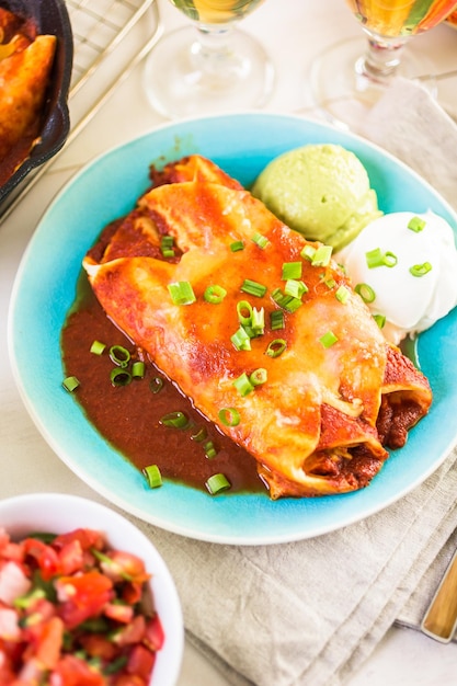 Foto piatto piano con enchiladas di pollo guarnite con cipolle verdi e panna acida.