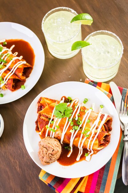 Dinner plate with Chicken enchiladas garnished with green onions and sour cream.