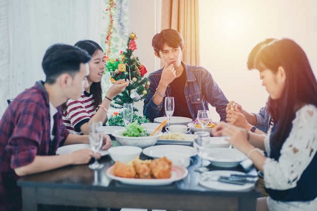 함께 부엌에서 식사 테이블에 앉아 저녁 음료를 즐기는 가장 친한 친구의 아시아 그룹과 저녁 식사