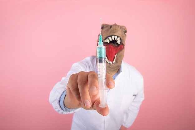 Dinosaur doctor holding a syringe closeup selective focus on an isolated pink background