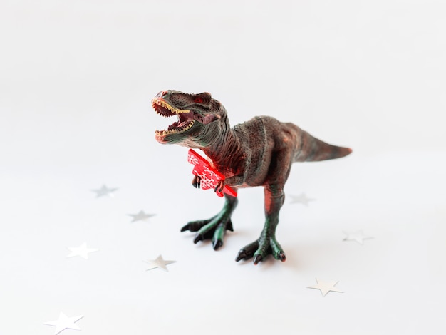 Dinosaur with red Christmas tree. Plastic toy 