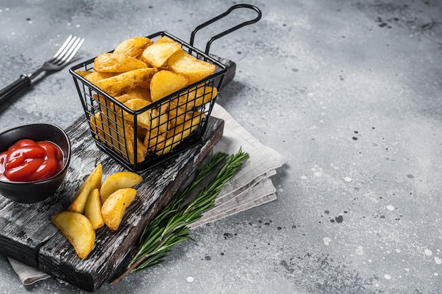 Dip gebakken aardappelpartjes met rozemarijn en tomatensaus in een mand Grijze achtergrond Bovenaanzicht Kopieer de ruimte