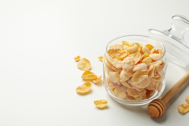 Dipper and jar of cornflakes on white background