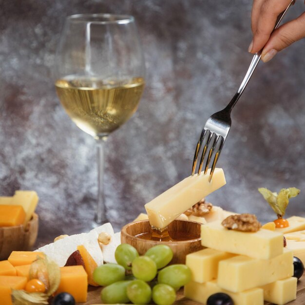 Photo dipping cheese to honey with forkplatter snacks and white wine overhead