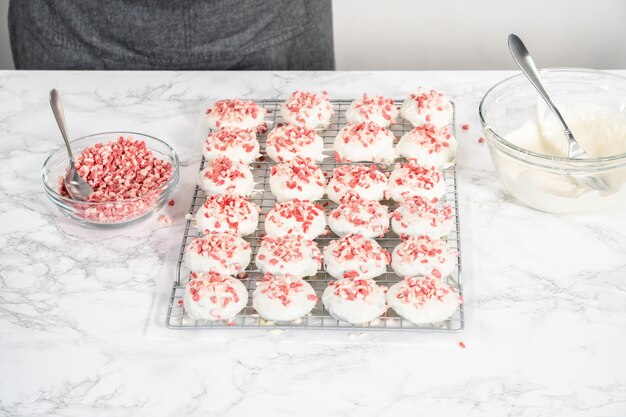 Dipping chocolate cookies into the melted white chocolate to prepare peppermint white chocolate cookies.