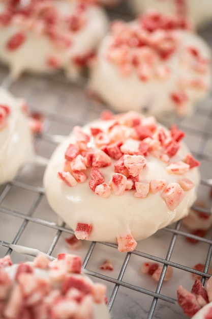 Dipping chocolate cookies into the melted white chocolate to prepare peppermint white chocolate cookies