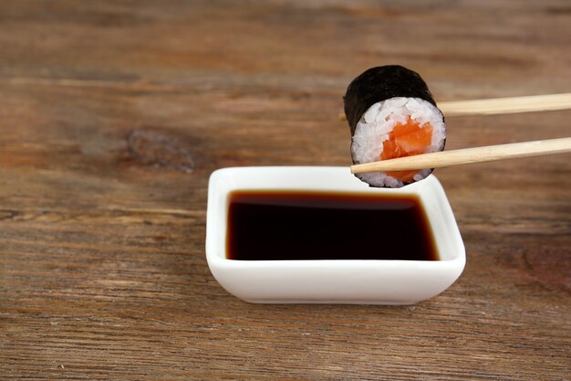 Photo dipping roll in sauce on wooden table