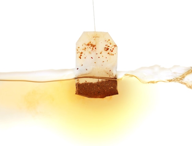 Dipping of tea bag into hot water against white background