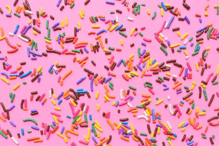 Foto direct boven confetti op een roze achtergrond.