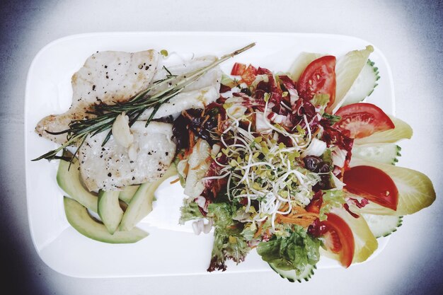 Foto direct boven de shot van geroosterde vis en salade geserveerd op een bord