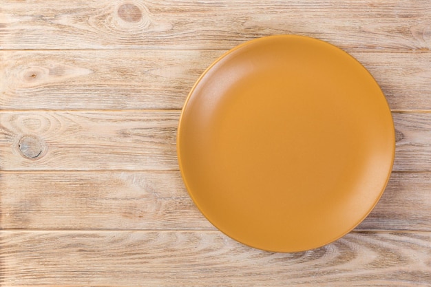 Foto direct boven lege gele matte schotel voor het diner op oranje houten achtergrond met kopieerruimte