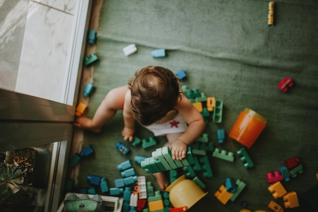 Direct boven opname van baby meisje dat thuis met speelgoed speelt