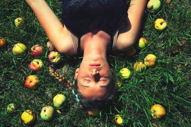 Direct boven opname van een jonge vrouw die rusten bij appels op het veld