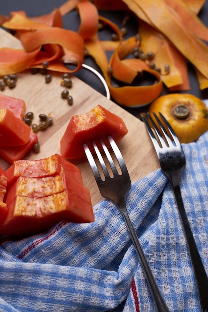 Direct boven opname van papaya-snijden met vork en servet op de snijplank