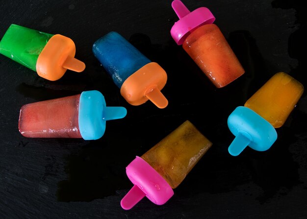 Foto direct boven opname van veelkleurige popsicles op zwarte achtergrond