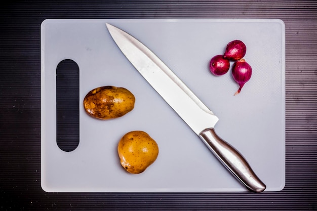 Direct boven schot van aardappelen en uien op snijplank boven tafel