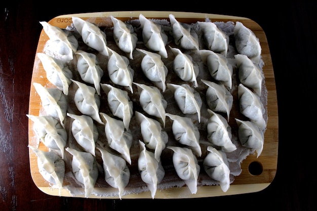 Direct boven schot van dumplings op snijplank op zwarte achtergrond
