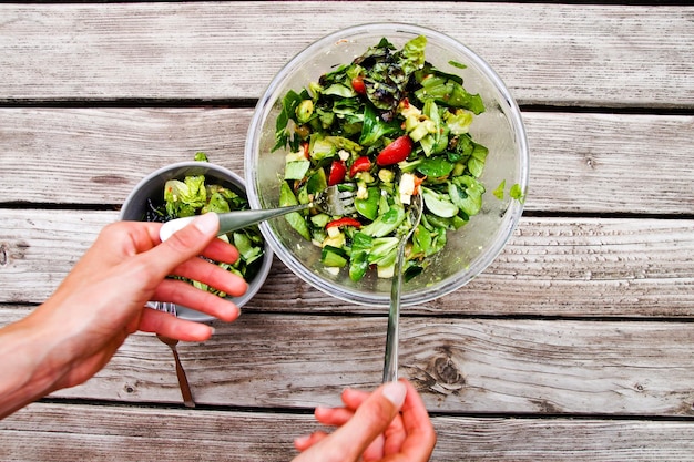 Foto direct boven schot van hand mengen salade in schaal op tafel