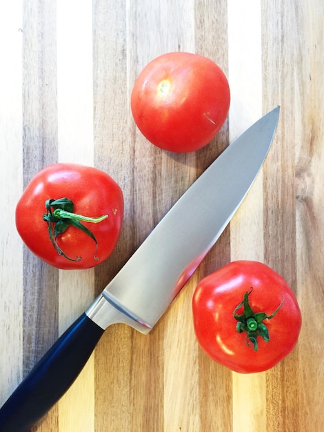 Direct boven schot van keukenmes en tomaten op houten tafel