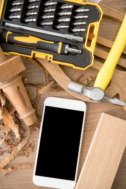 Direct boven schot van mobiele telefoon met hout en handgereedschap op tafel