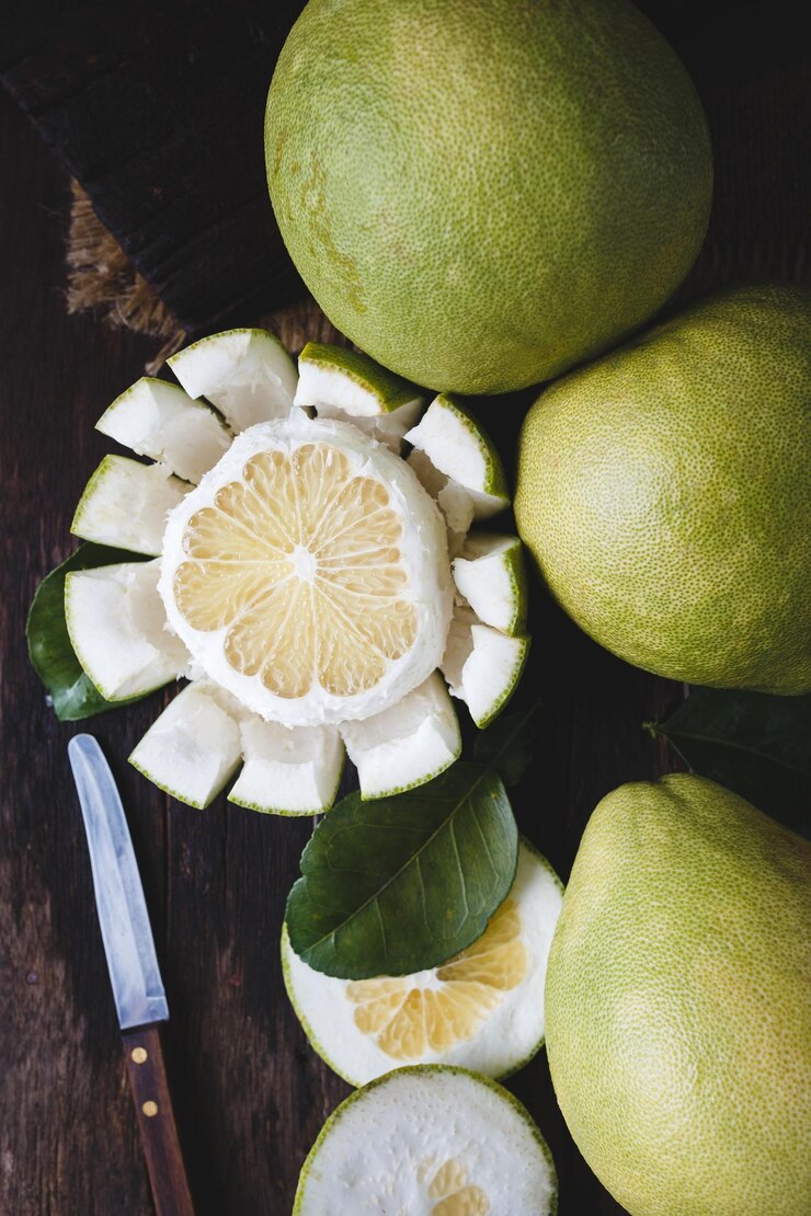 Foto direct boven schot van pomelos en mes op houten tafel.