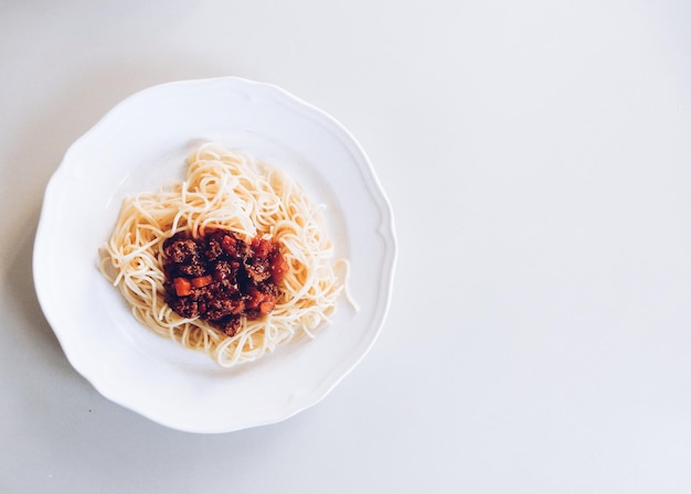 Direct boven schot van spaghetti geserveerd op een bord tegen een witte achtergrond