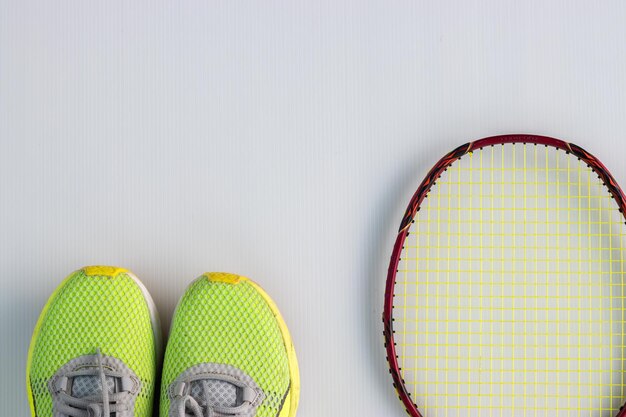 Foto direct boven schot van sportschoen en racket op tafel