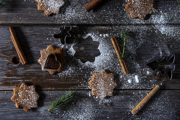Direct boven schot van suikerpoeder over koekjes en kaneel op houten tafel