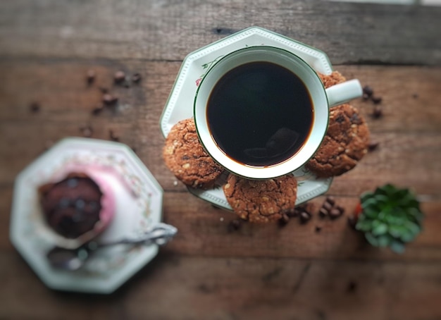 Direct boven schot van zwarte koffie en koekjes op tafel