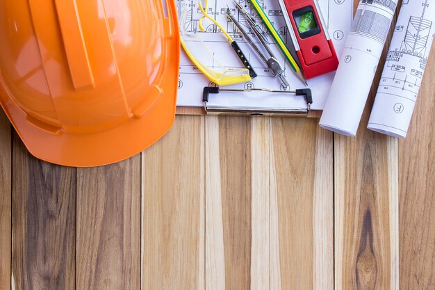 Direct boven shot van oranje hardhat met werktuigen en blauwdrukken hardhouten vloer