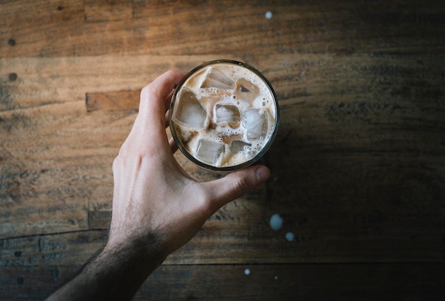 Direct boven uitzicht van man die koude koffie vasthoudt
