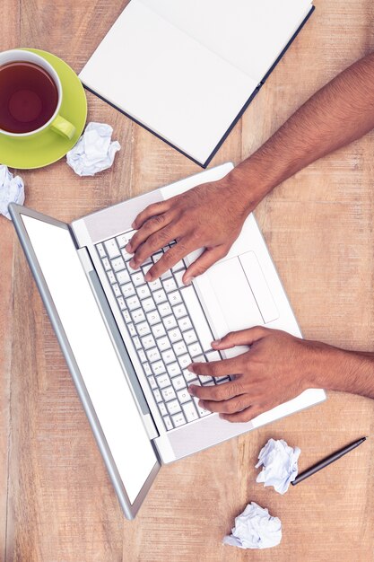 Direct geschoten van beklemtoonde zakenman die laptop met behulp van bij bureau in bureau